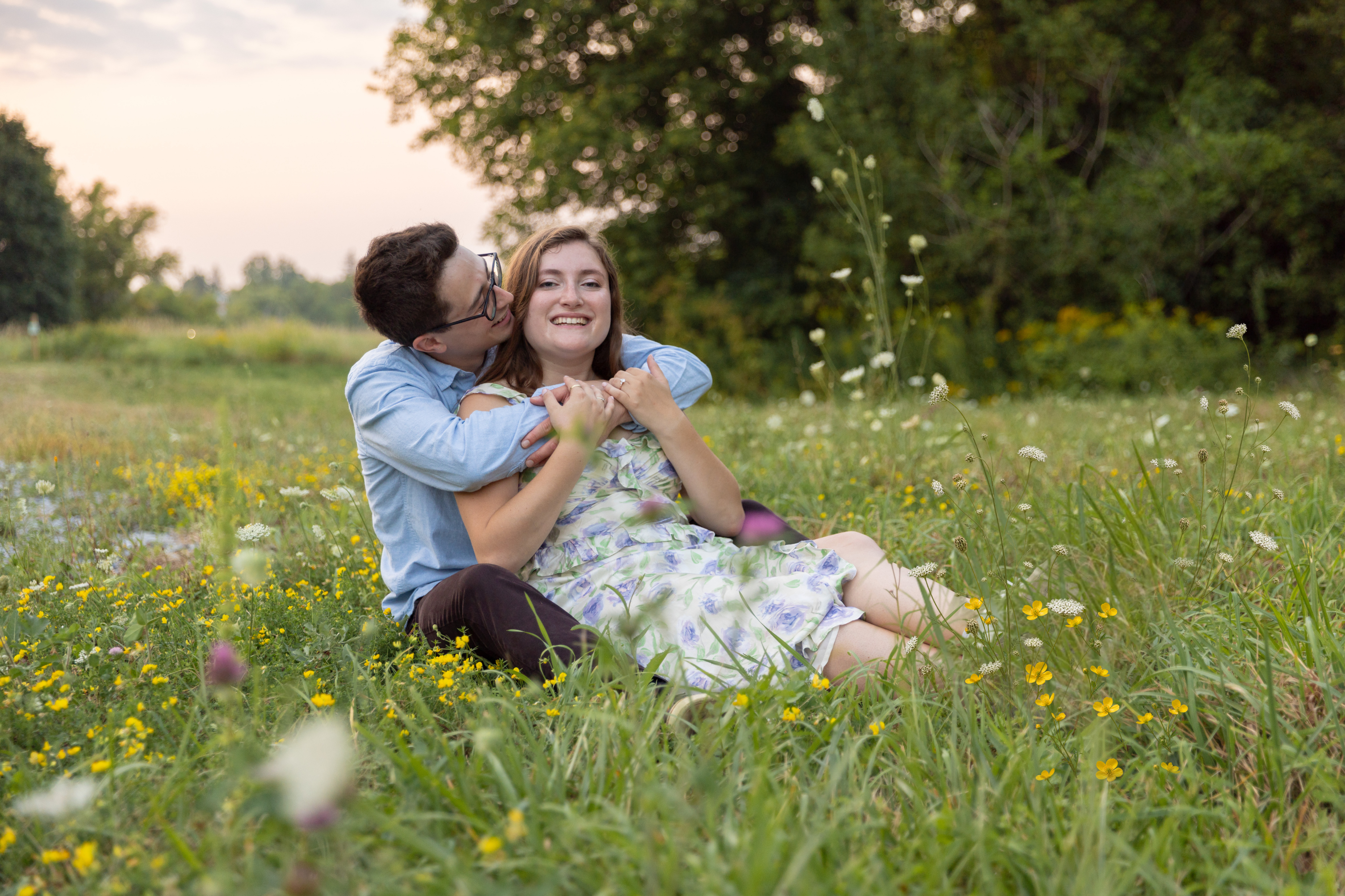 Sarah and Syl sitting together in a wildflower meadow at dusk